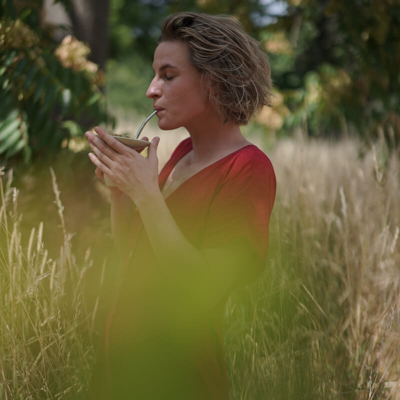 Frau trinkt caámate Bio Mate Tee in der cuia im Feld