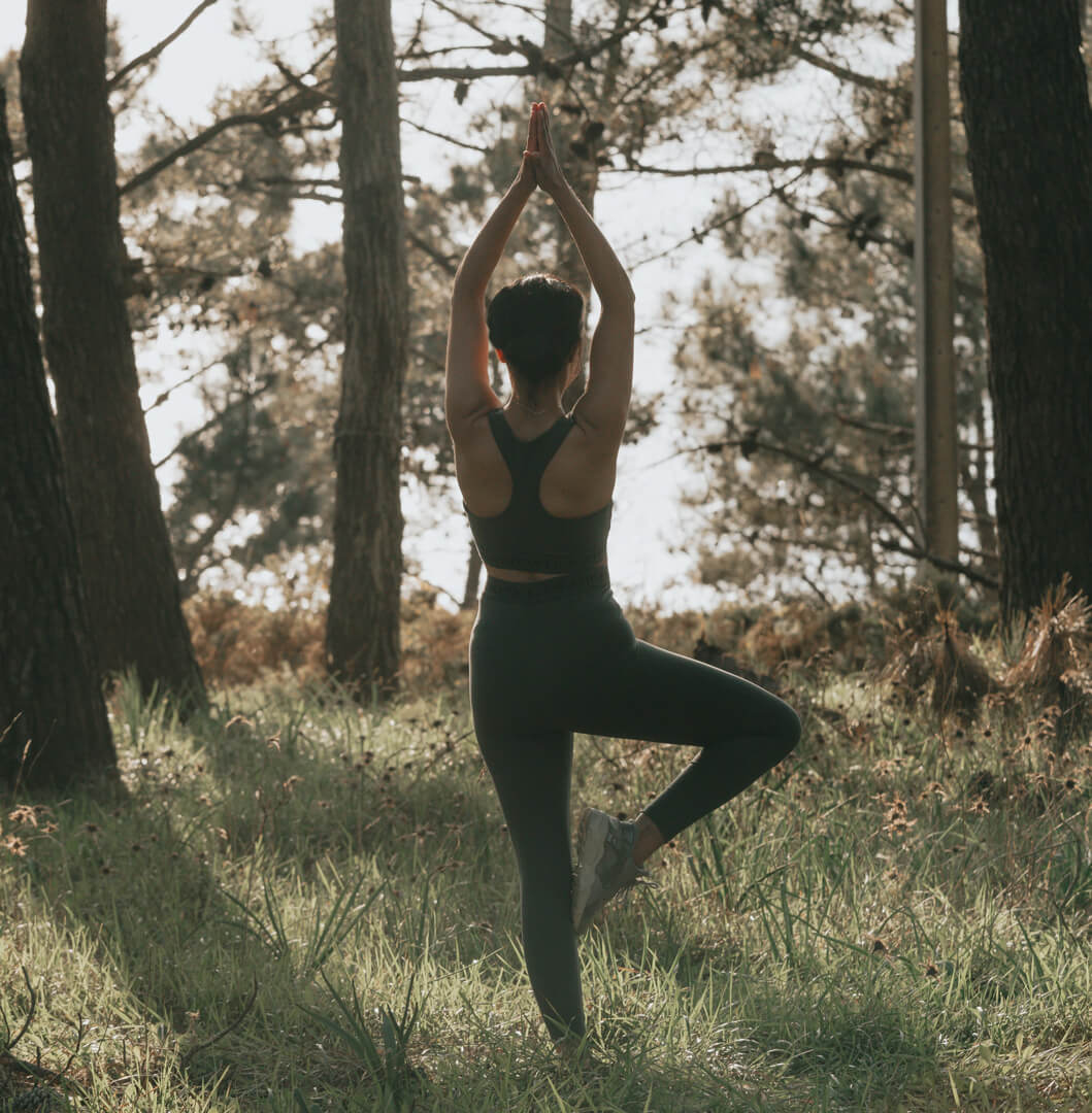 Frau beim Yoga im Wald mit Mate Tee